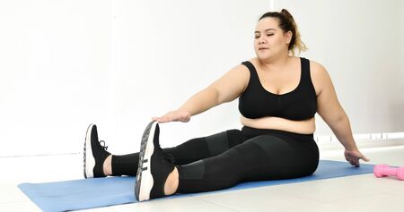 Chubby woman doing streching in a room.の写真素材