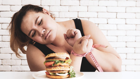 Chubby woman prohibit herself to eat hamburger.
