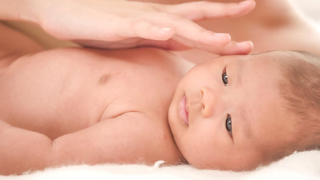 Woman's hand touching on baby's face.