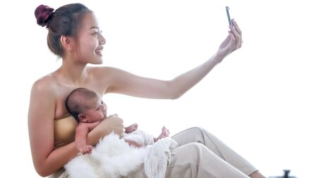 Happy mother taking photos with baby in the room.の写真素材