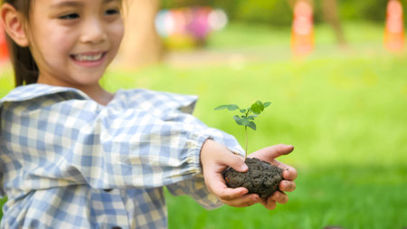 Happy asian girl holding young plant at garden.の写真素材