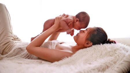 Happy mother taking care of baby in the room.の写真素材