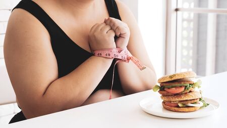 Chubby woman prohibit herself to eat hamburger.の写真素材