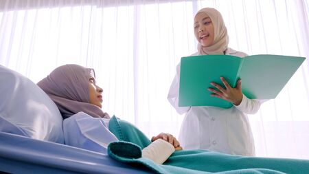 Muslim female doctor talking with patient at hospital room.の写真素材