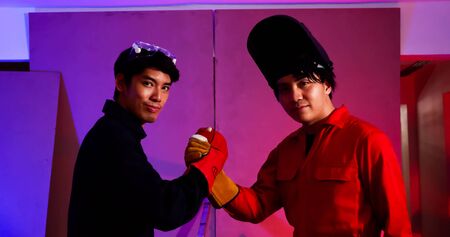 Successful male welders touching hands together at siteの写真素材
