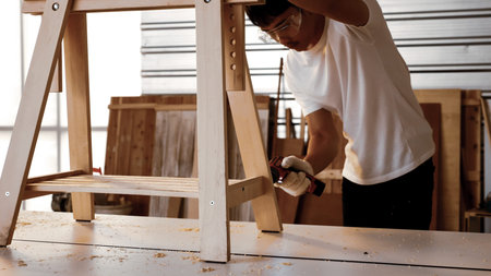Carpenter using drill to screwing pieces of board at site.