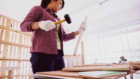 Female carpenter using hammer to driving nail in board at site.の写真素材