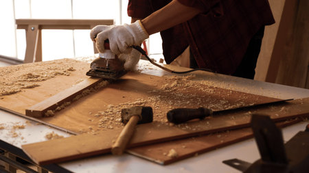 Carpenter using electric planer to shaving board at site.