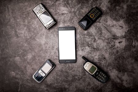 Many obsoleted cellphones and a smartphone on a grungeの写真素材