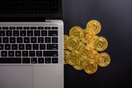 Computer and golden coins with bitcoin symbol on a black background.の写真素材
