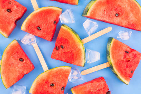 Watermelon slices on sticks  ice cubes. Fresh watermelon on blue background.の写真素材