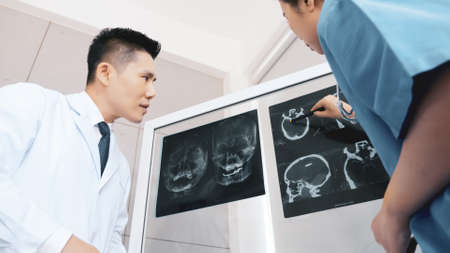Doctor and medical assistants discussing about diagnosis result on x-ray film.の写真素材