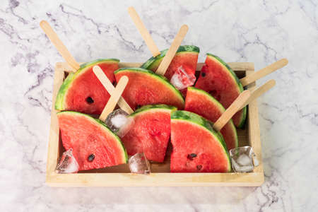 Watermelon slices on sticks  ice cubes. Fresh watermelon in wooden bowl.の写真素材