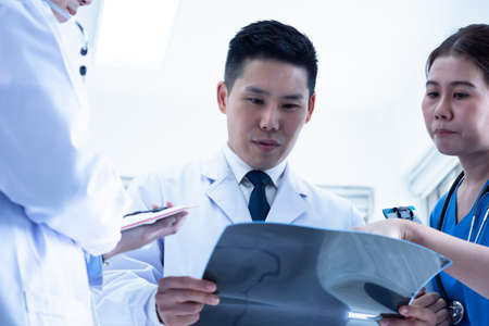 Doctor and medical assistants discussing about diagnosis result on x-ray film.の写真素材