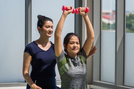 Two asian women doing yoga together at a gym.