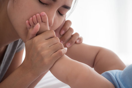Mother kissing on newborn baby foot.
