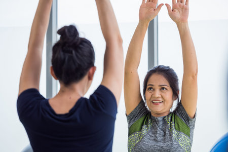 Two asian women doing yoga together at a gym.