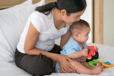 Asian mother taking care of newborn baby in a bedroom.