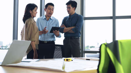 Team of young Asian architects discussing on construction site.の写真素材
