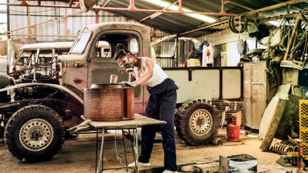 Attractive young woman mechanical worker repairing a vintage car in old garage.の写真素材
