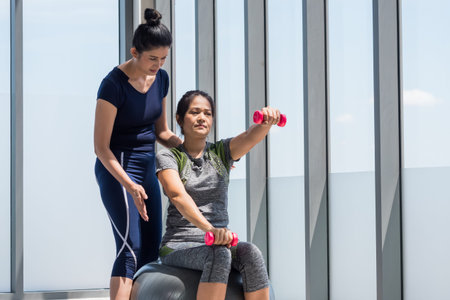 Two asian women doing yoga together at a gym.