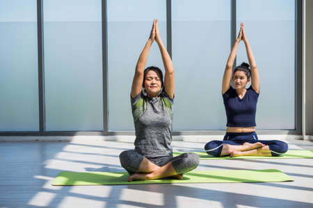 Two asian women doing yoga together at a gym.の写真素材