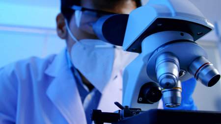 Asian scientist doing some research and looking through a microscope in laboratory.