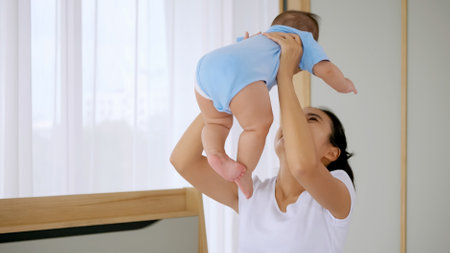 Young mother with her little baby playing on bed at home.の写真素材