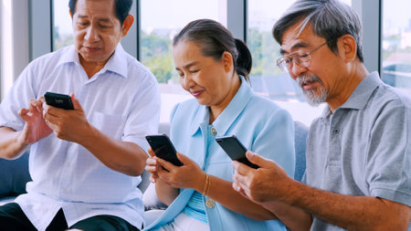 Group of senior friends using smart phone in a retirement homeの写真素材
