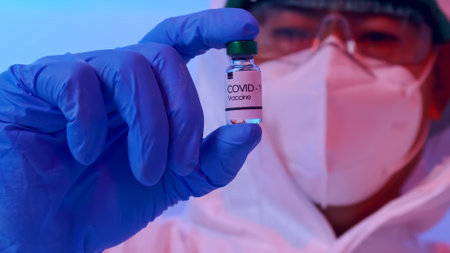 Scientist in PPE suit conducts research on the COVID 19 vaccine at a laboratory.の写真素材