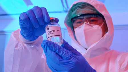 Scientist in PPE suit conducts research on the COVID 19 vaccine at a laboratory.