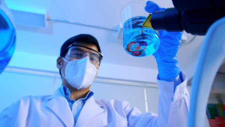 Asian scientist doing some research checking a liquid in a test flask at laboratory.の写真素材