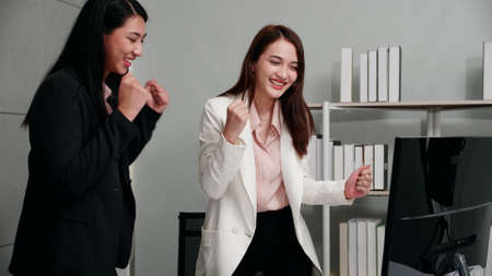 Two young business women expressed their joy at being successful in the project. Successful entrepreneurs achieving goals.の写真素材