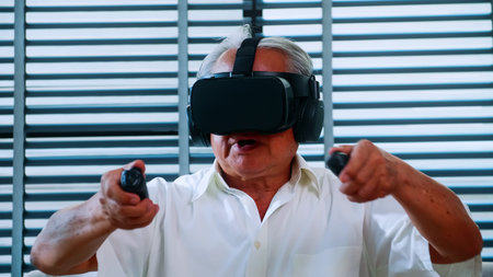 Asian senior man having fun playing video game with virtual reality glasses at home.