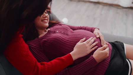 Happy pregnant lesbian couple spending time together at home.の写真素材