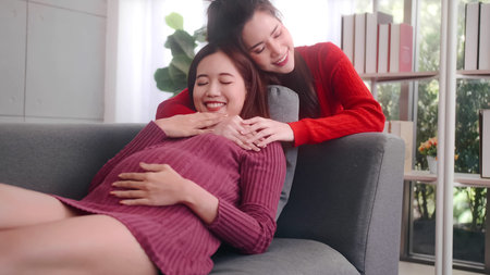 Happy pregnant lesbian couple spending time together at home.