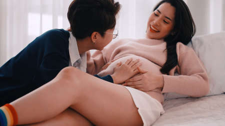 Pregnant Asian lesbian woman and her partner are happy to spend time together at home.の写真素材