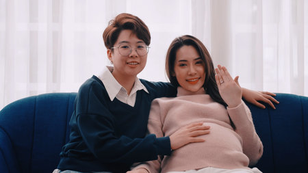 Pregnant Asian lesbian woman and her partner are happy to spend time together at home.の写真素材
