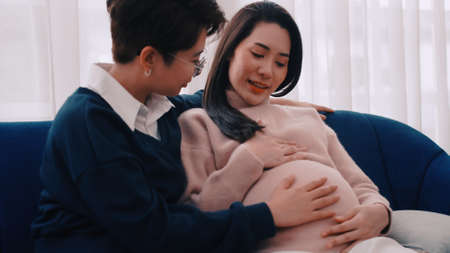 Pregnant Asian lesbian woman and her partner are happy to spend time together at home.の写真素材