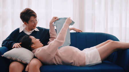 Pregnant Asian lesbian woman and her partner are happy to spend time together at home.の写真素材