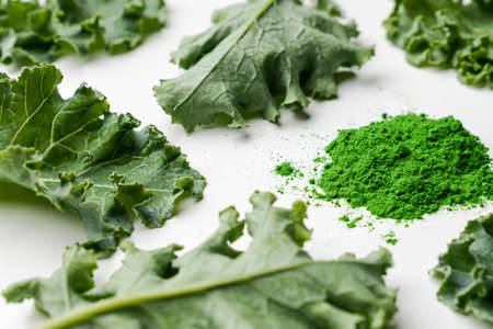 Green leaves of kale and kale powder on white background.の写真素材