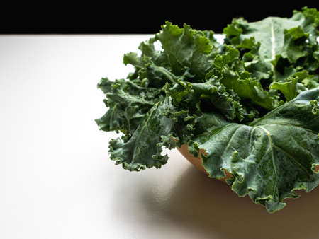 Green leaves of kale in a bowl on white table.の写真素材