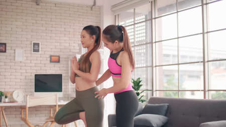 Two Asian girls doing yoga exercises at home.の写真素材