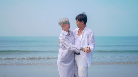 Asian retired couple relaxing by the sea in summer. A senior woman dancing with her partner on the...
