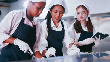Group of schoolgirls having fun learning to cook. Female students in a cooking class.の写真素材