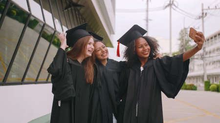 Group of friends having fun celebrating their graduation by taking pictures together.の写真素材