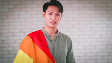 Portrait of Asian gay man holding a rainbow flag.