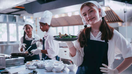 Group of schoolgirls having fun learning to cook. Female students in a cooking class.の写真素材