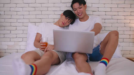 Happy gay Asian couple spending time together in bed at home.の写真素材