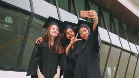 Group of friends having fun celebrating their graduation by taking pictures together.の写真素材